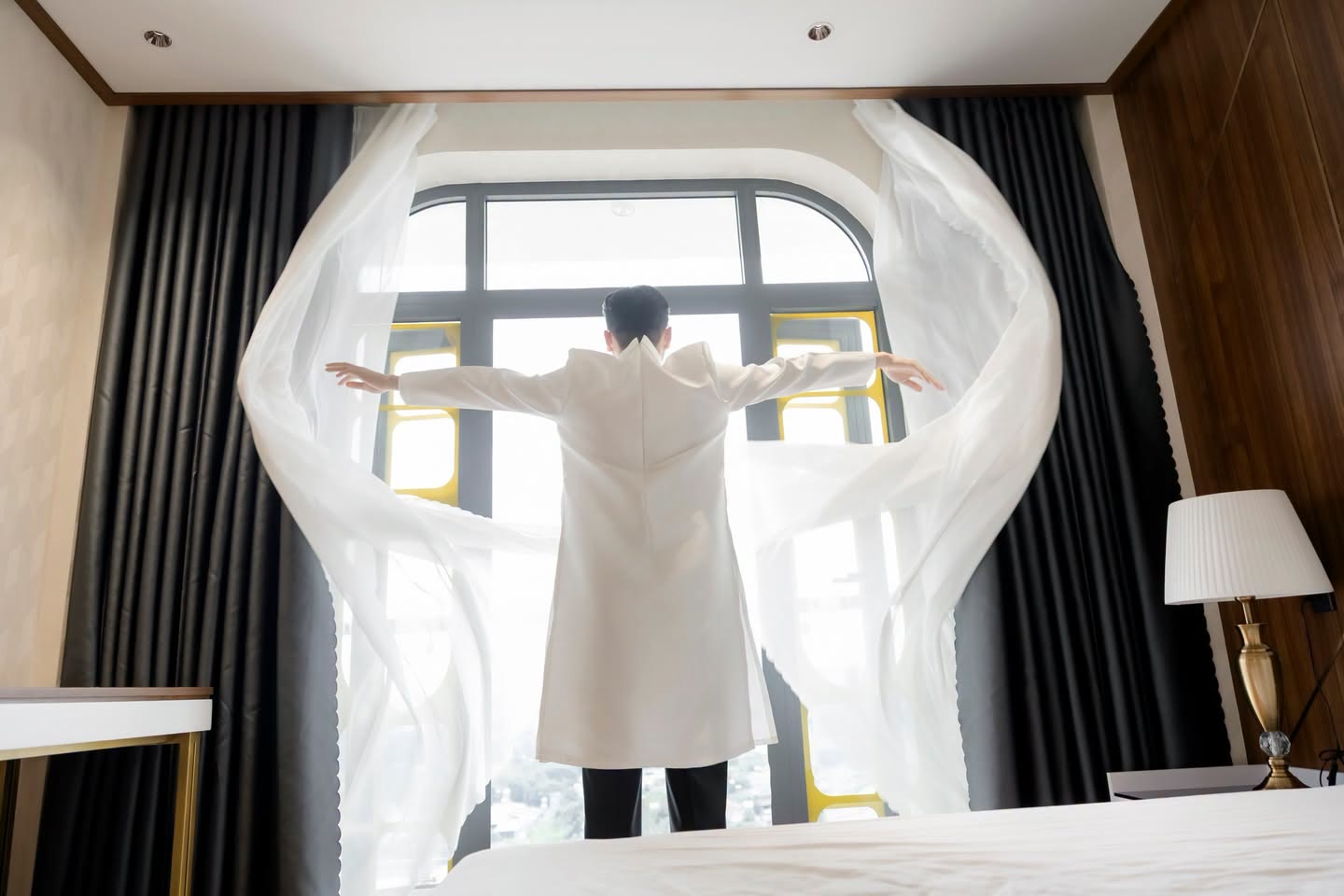 Chú rể dang tay bên cửa sổ rèm trắng